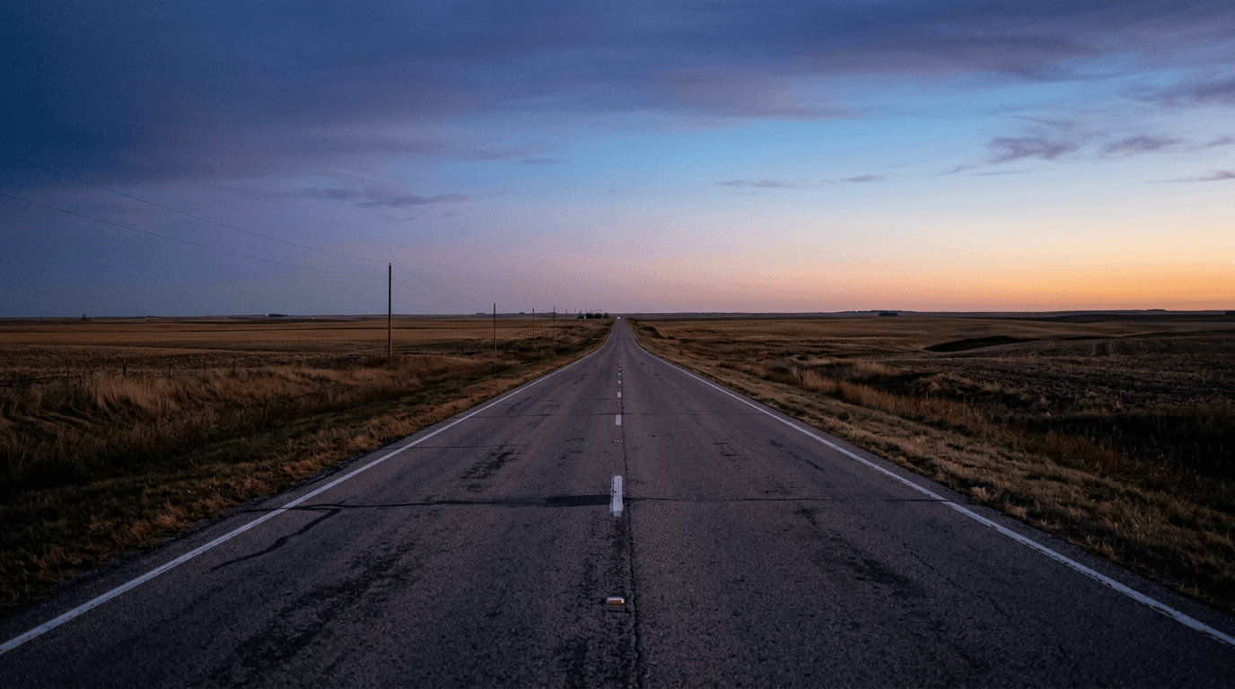 A solitary highway stretching into a vast, empty Kansas landscape at dusk, symbolizing the impact of the Kansas transgender license revocation.